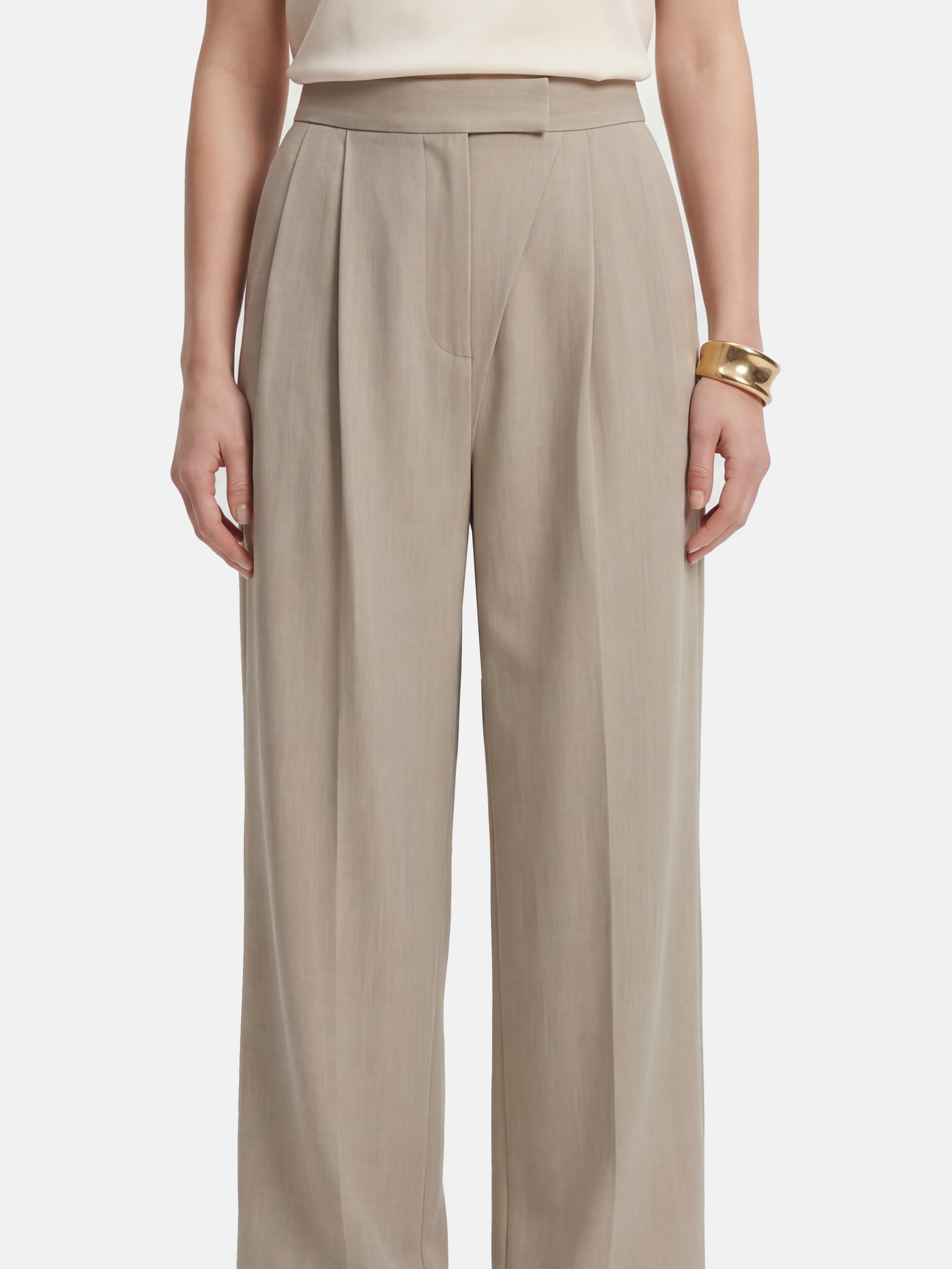 Cropped wide-leg trousers in quiet khaki, featuring deep pleats and an asymmetric front, embodying architectural form and fluid motion.