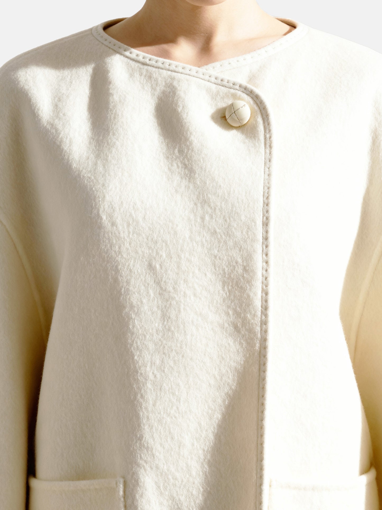 SELVANE asymmetric single-button wool coat in calm ivory, featuring a clear line and composed silhouette.