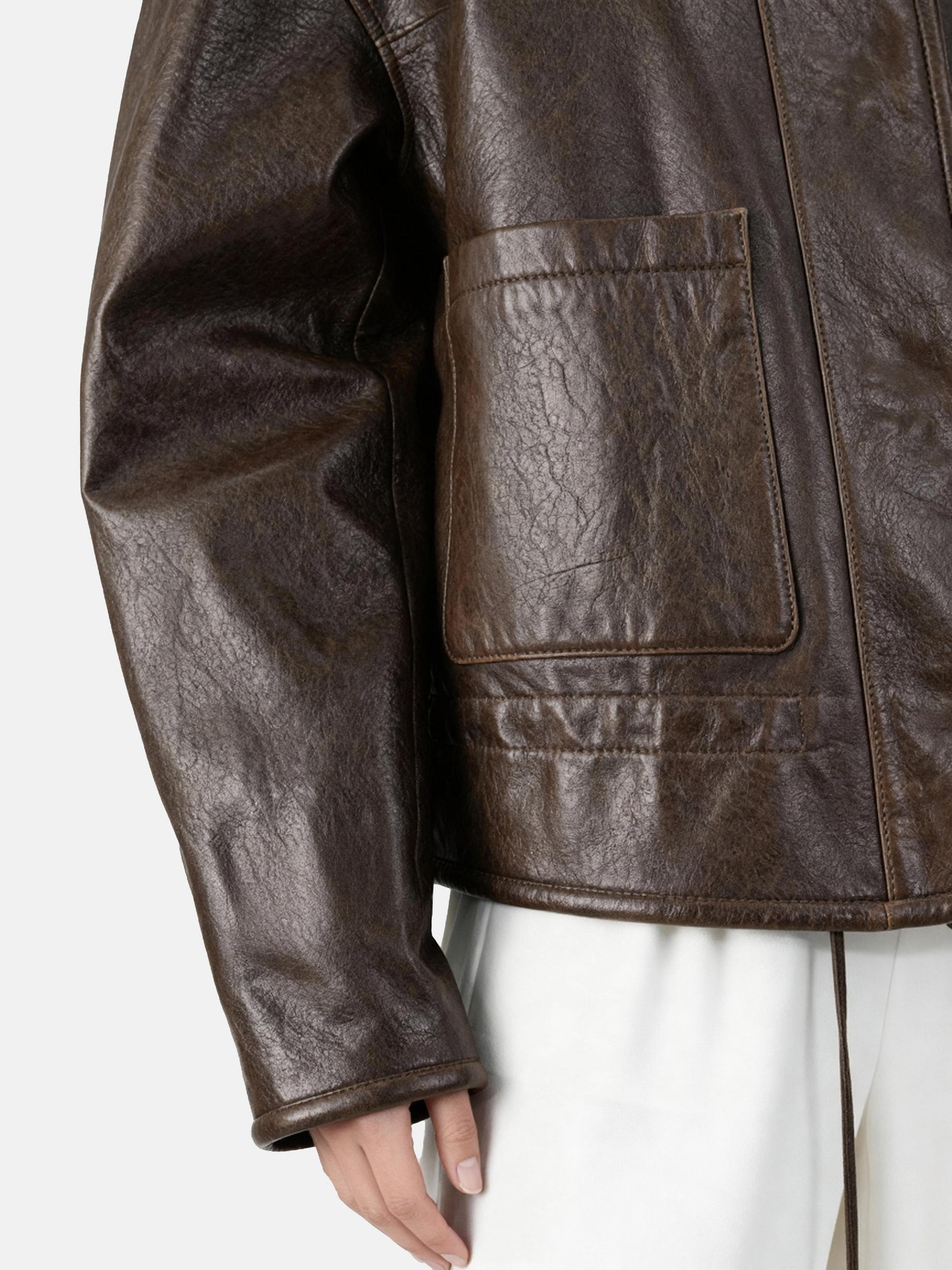 SELVANE brown lambskin crew-neck jacket with softened volume and drawstring hem, showcasing clean lines and supple texture.