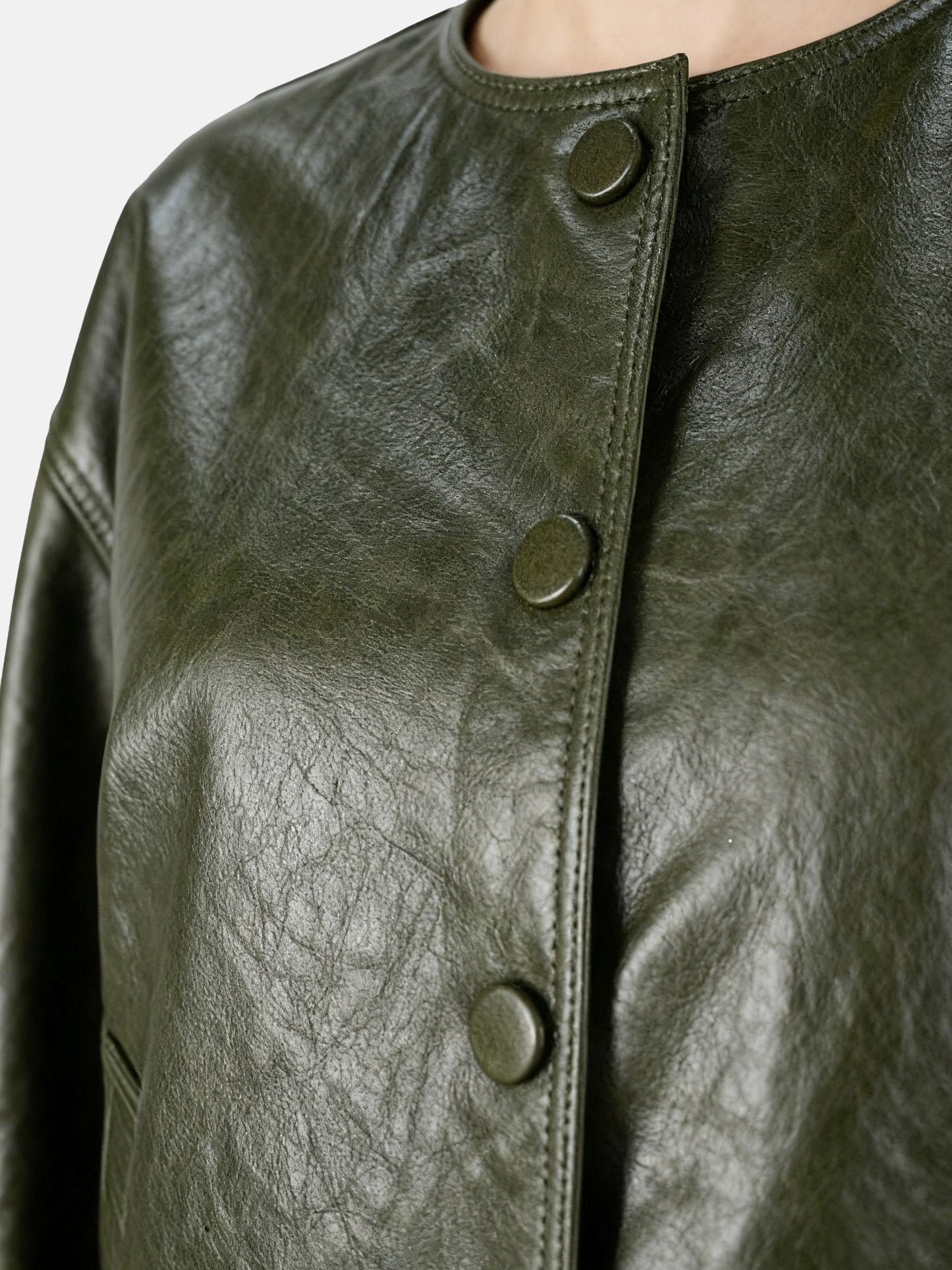 Cropped olive lambskin jacket with a clean round neckline and tonal buttons, showcasing a precise, composed silhouette.