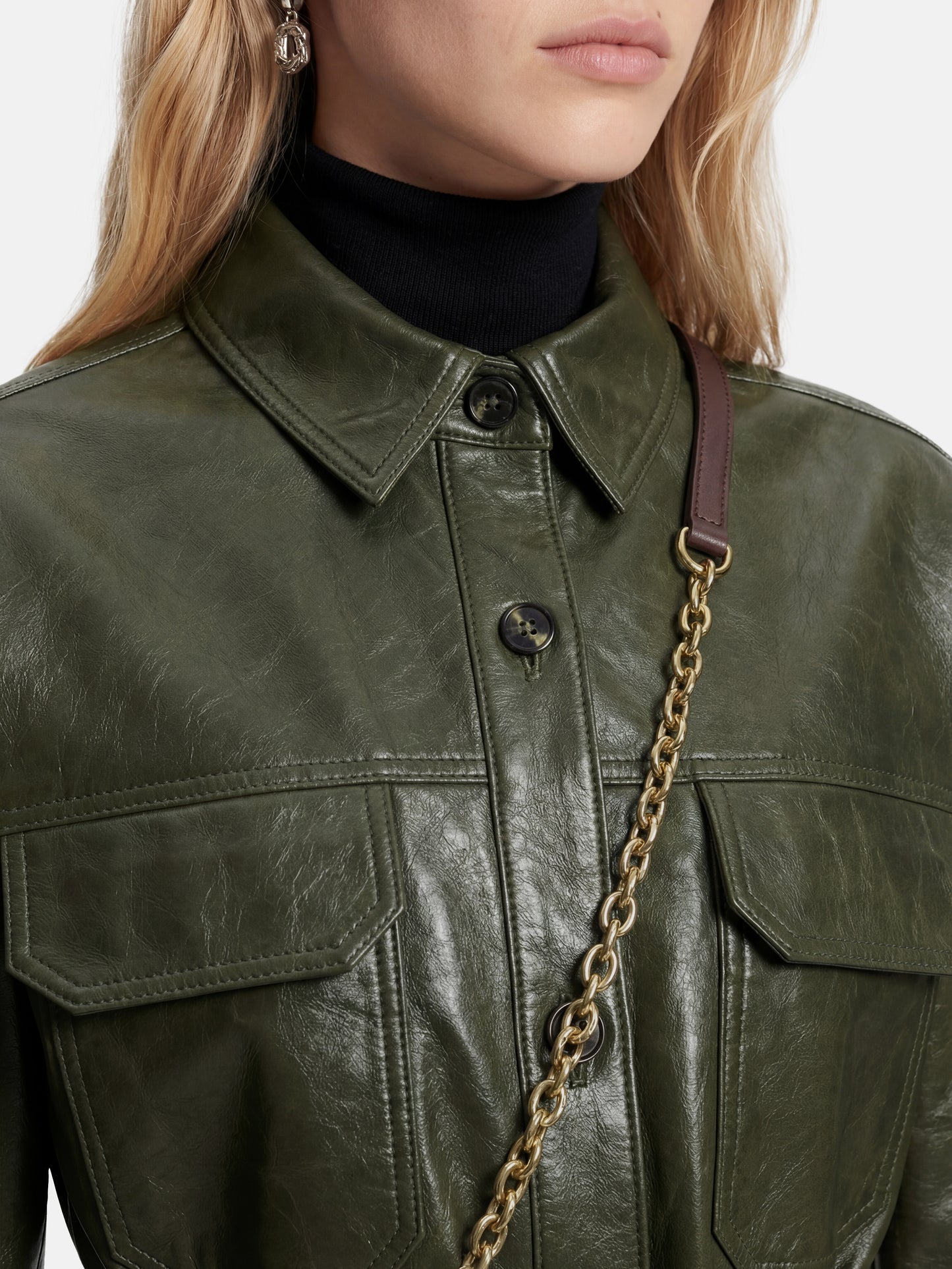 Olive lambskin belted shirt jacket with straight shoulders, cinched waist, and mid-thigh length, shown in motion.