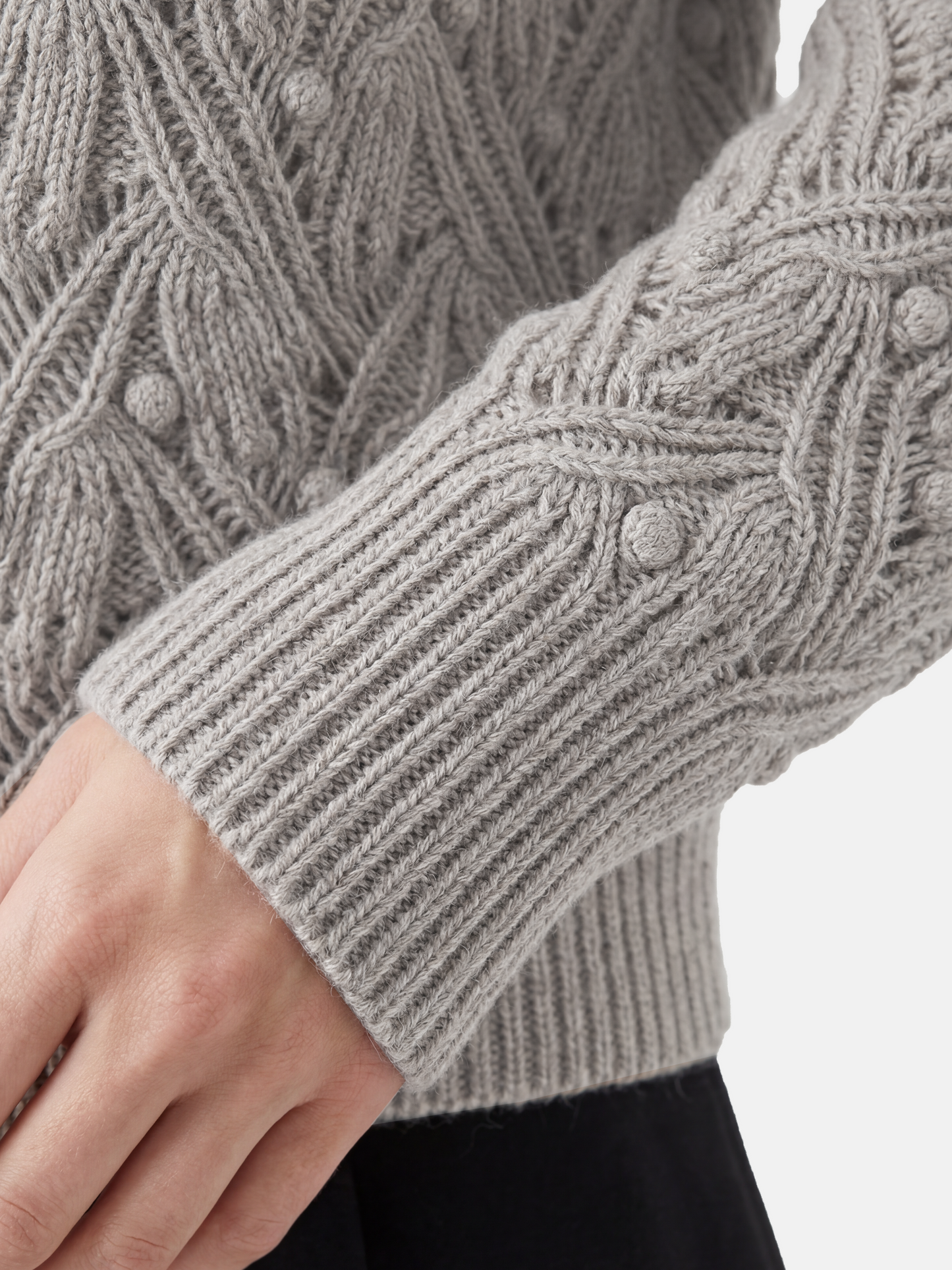 Cropped soft grey cashmere mock-neck cable sweater with sculpted texture, shown on a model, conveying quiet warmth and refined presence.