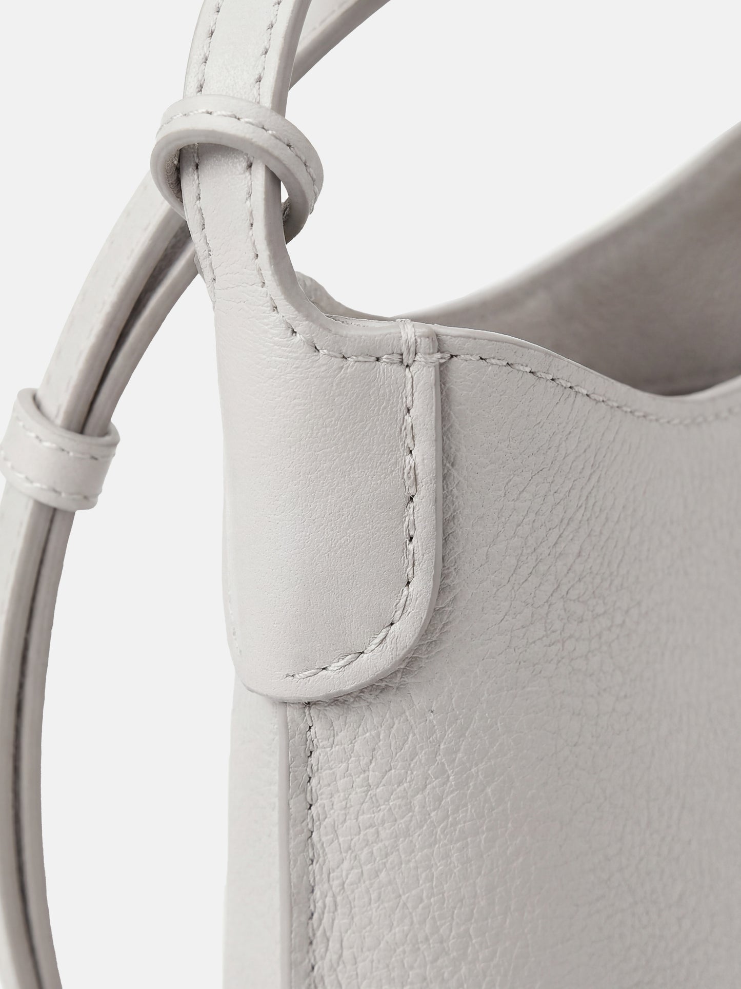 SELVANE Leather Mini Bucket Bag in Bonaudo cow leather, featuring soft vertical lines, a curved top, and long strap, sitting neatly.