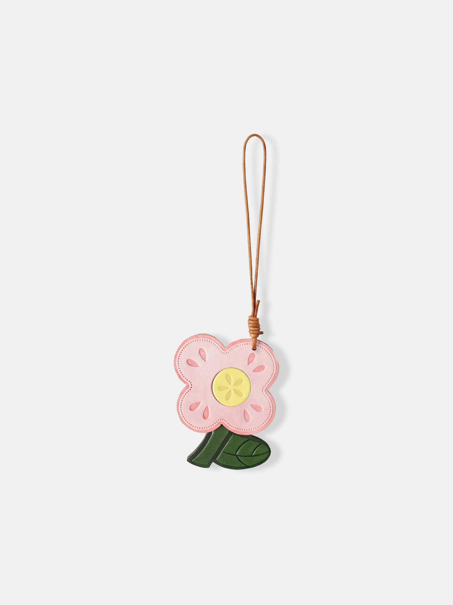 Selvane Flower Bag Charm, a graphic leather bloom with rounded petals and a cutout motif, suspended by a slender lanyard.