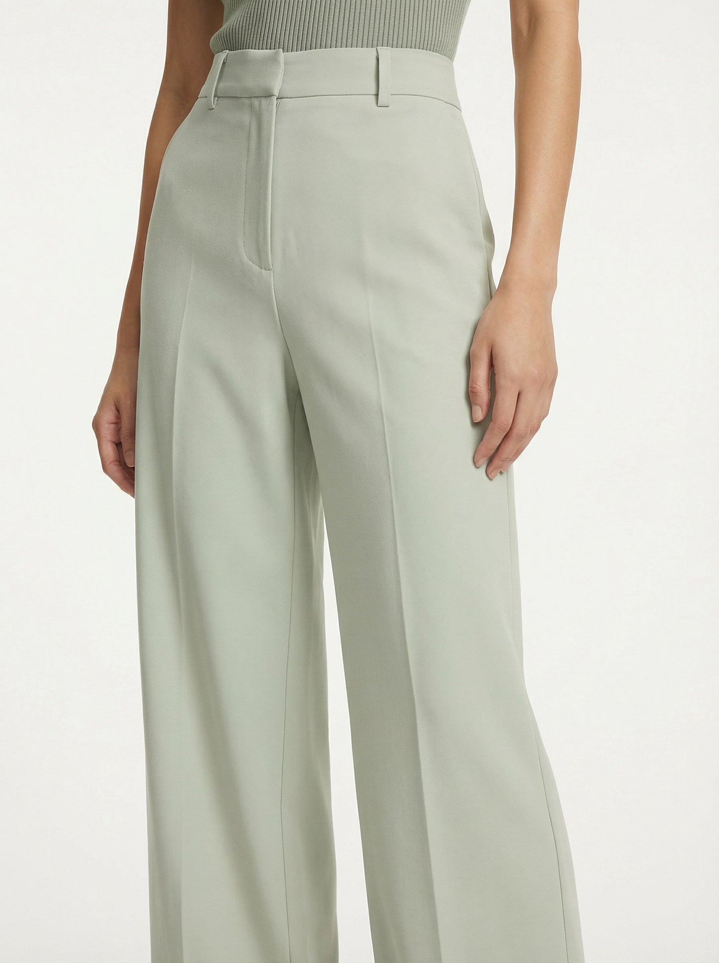 Model wearing SELVANE sage green ribbed knit tank and high-waisted wide-leg trousers set, standing elegantly.