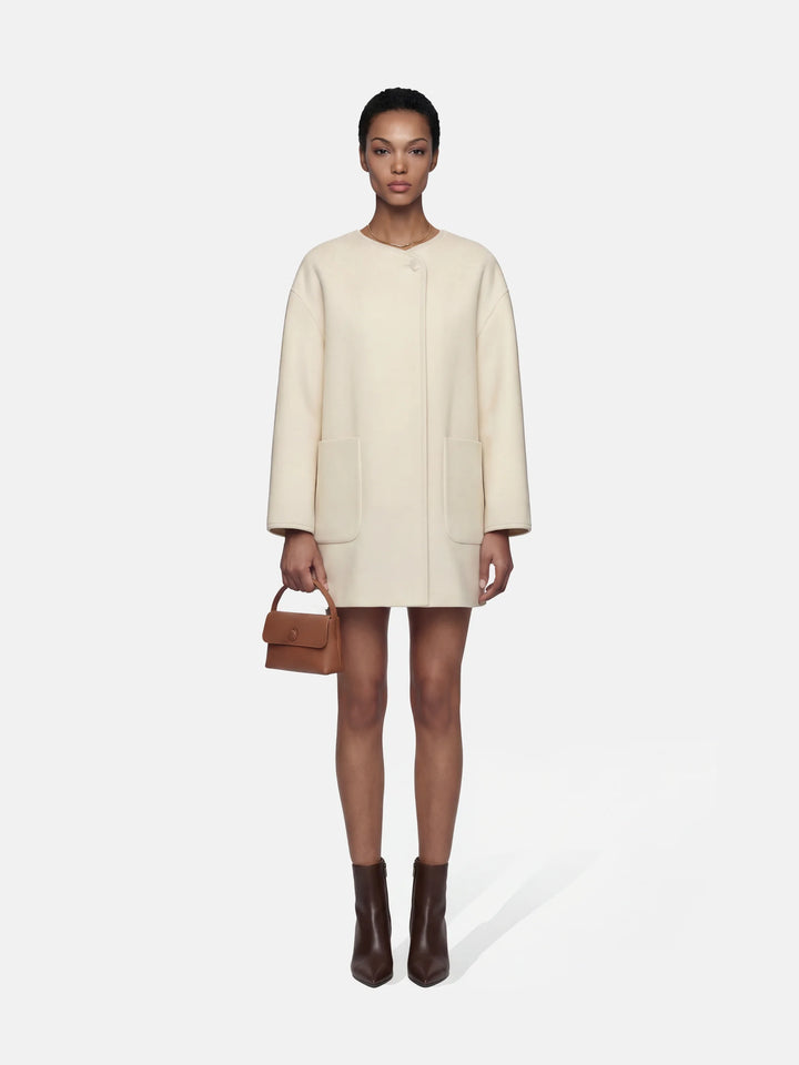 SELVANE asymmetric single-button wool coat in calm ivory, featuring a clear line and composed silhouette.