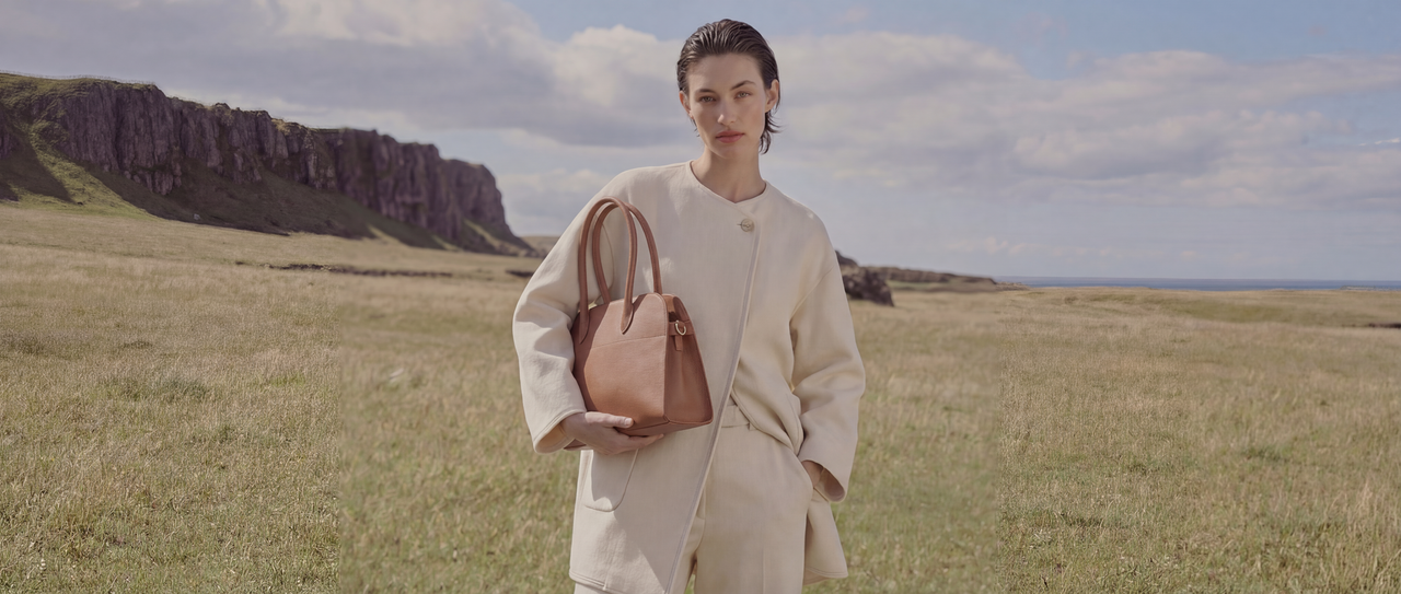 A structured top-handle bag in deep navy saddle leather—clean curves, steady volume, designed to look composed from morning to night