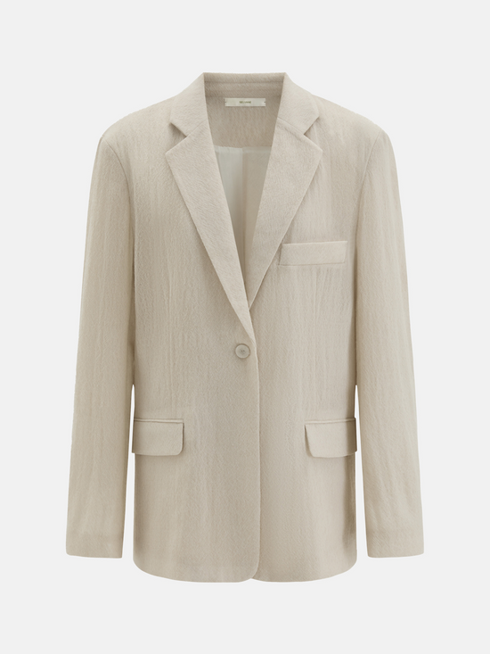 Structured worsted wool jacket with mulberry silk lining, tailored fit, shown on a model in a thoughtful pose.