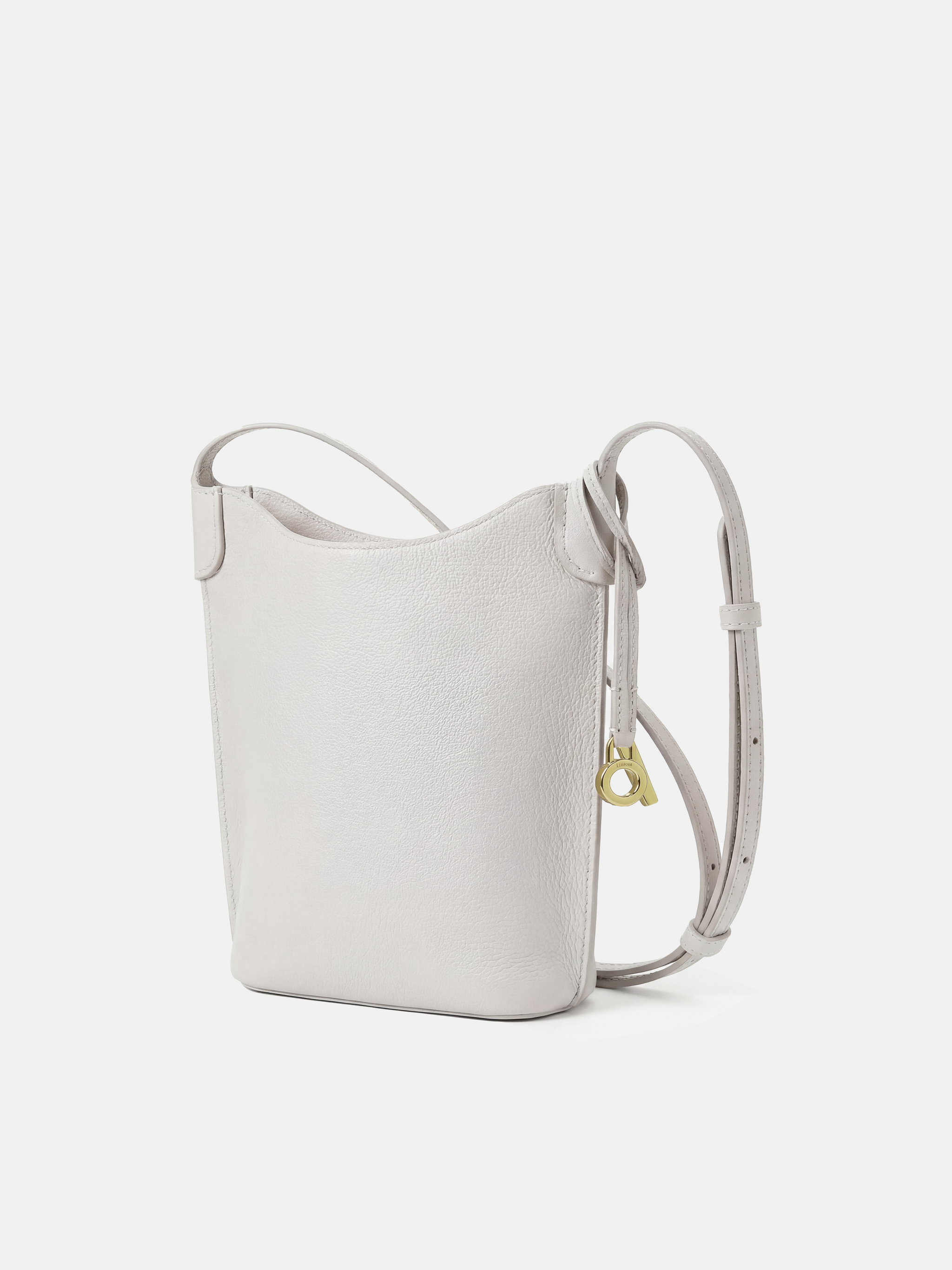 SELVANE Leather Mini Bucket Bag in Bonaudo cow leather, featuring soft vertical lines, a curved top, and long strap, sitting neatly.