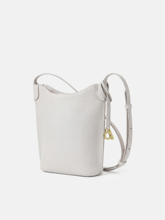 SELVANE Leather Mini Bucket Bag in Bonaudo cow leather, featuring soft vertical lines, a curved top, and long strap, sitting neatly.