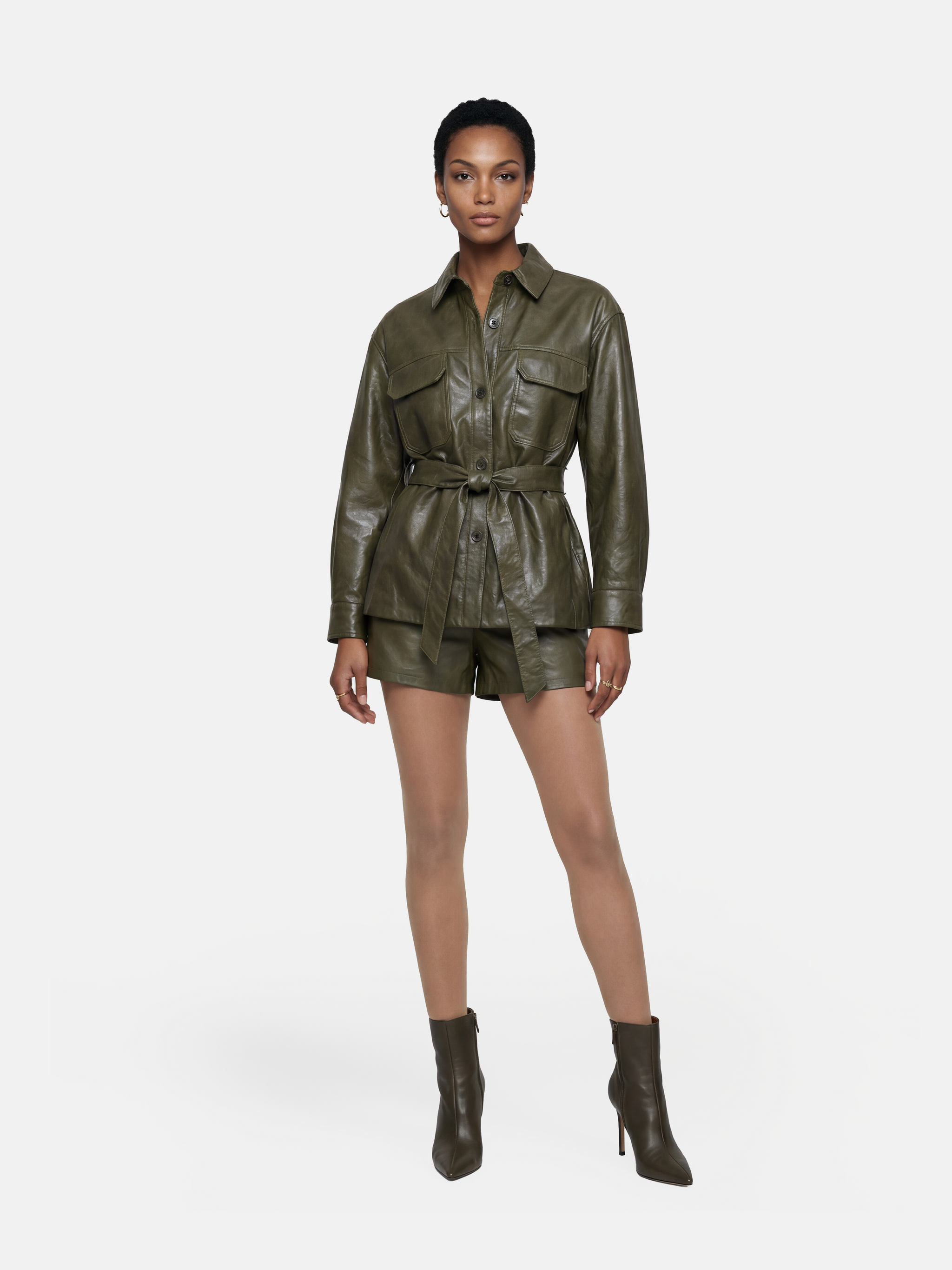 Olive lambskin belted shirt jacket with straight shoulders, cinched waist, and mid-thigh length, shown in motion.