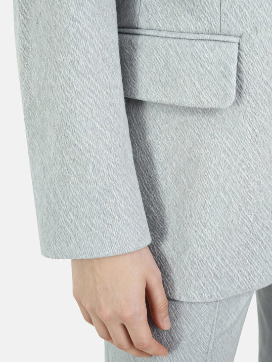 Structured worsted wool jacket with mulberry silk lining, tailored fit, shown on a model in a thoughtful pose.