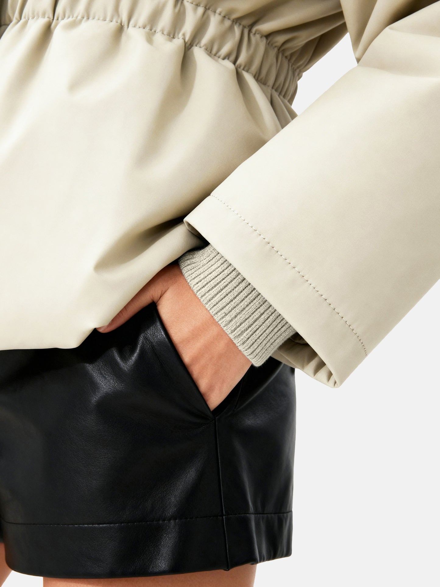 Apricot high-collar structured puffer down jacket by SELVANE, featuring a concealed placket and cinched waist, presented architecturally.