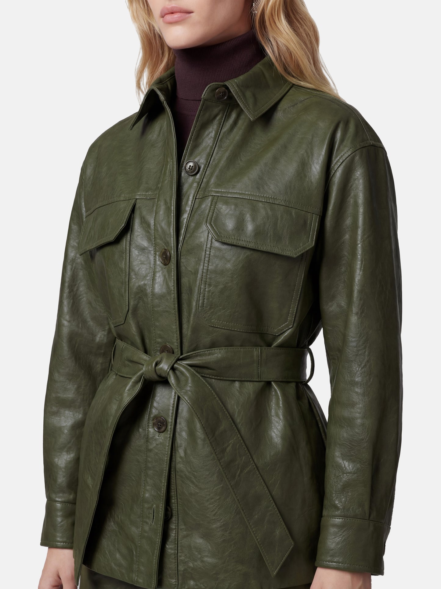 Olive lambskin belted shirt jacket with straight shoulders, cinched waist, and mid-thigh length, shown in motion.