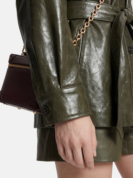 Olive lambskin belted shirt jacket with straight shoulders, cinched waist, and mid-thigh length, shown in motion.
