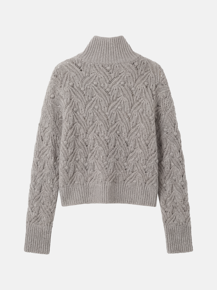 Cropped soft grey cashmere mock-neck cable sweater with sculpted texture, shown on a model, conveying quiet warmth and refined presence.