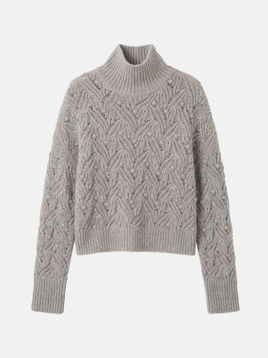 Cropped soft grey cashmere mock-neck cable sweater with sculpted texture, shown on a model, conveying quiet warmth and refined presence.