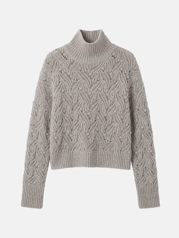 Cropped soft grey cashmere mock-neck cable sweater with sculpted texture, shown on a model, conveying quiet warmth and refined presence.