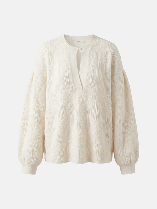 Relaxed ivory cashmere knit top featuring a clean round neck, deep slit, soft volume sleeves with neat cuffs, and a distinctive raised texture.