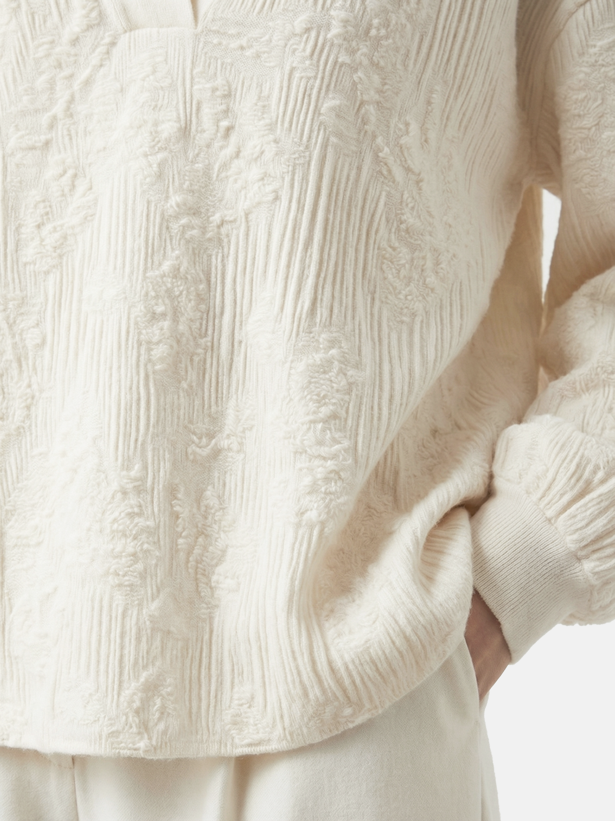 Relaxed ivory cashmere knit top featuring a clean round neck, deep slit, soft volume sleeves with neat cuffs, and a distinctive raised texture.