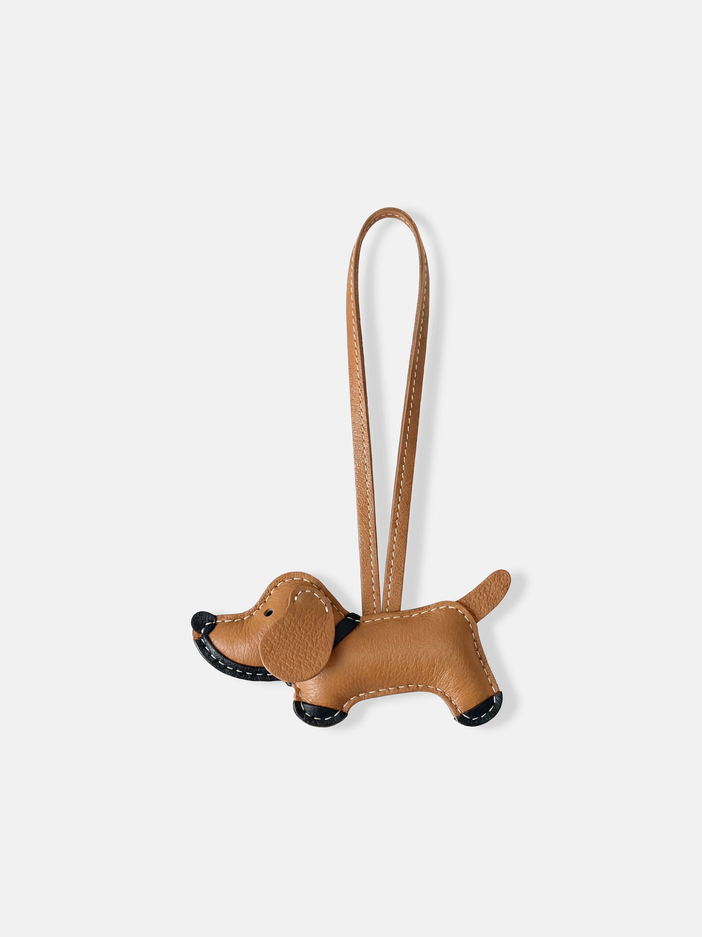 Small sculpted smooth leather dachshund bag charm with clean top-handle loop and contrast stitching, front view.