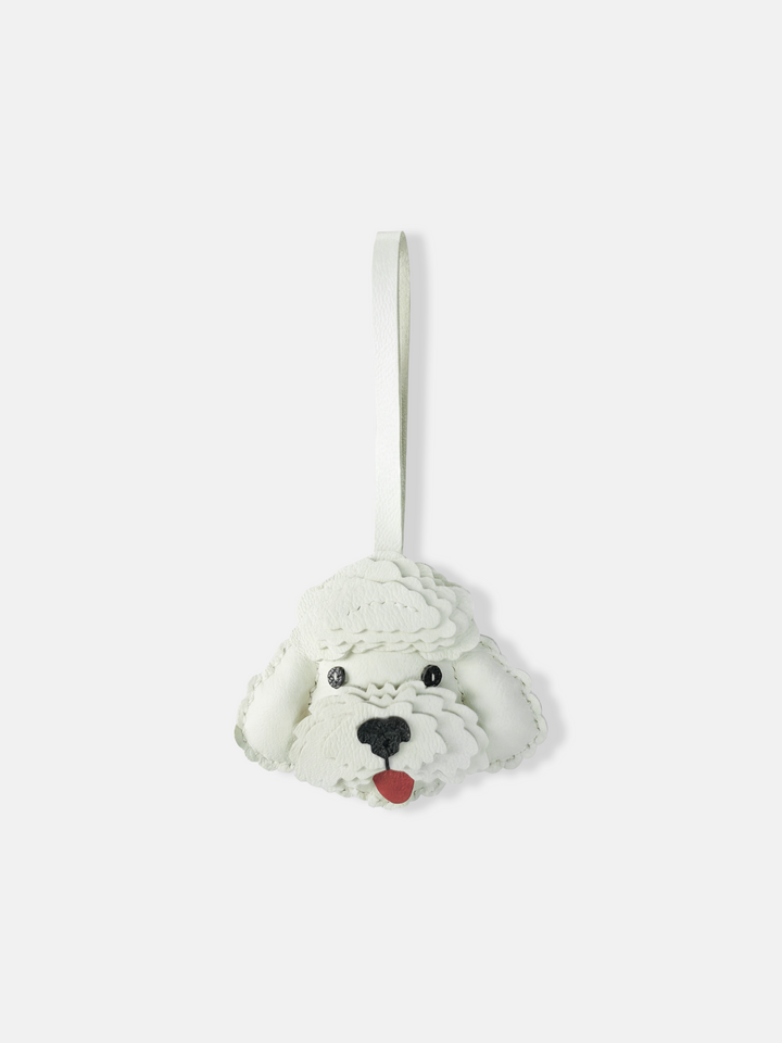 Close-up of Selvane Curly Pup Bag Charm, a sculpted emblem with soft curves and layered contours, attached to a bag.