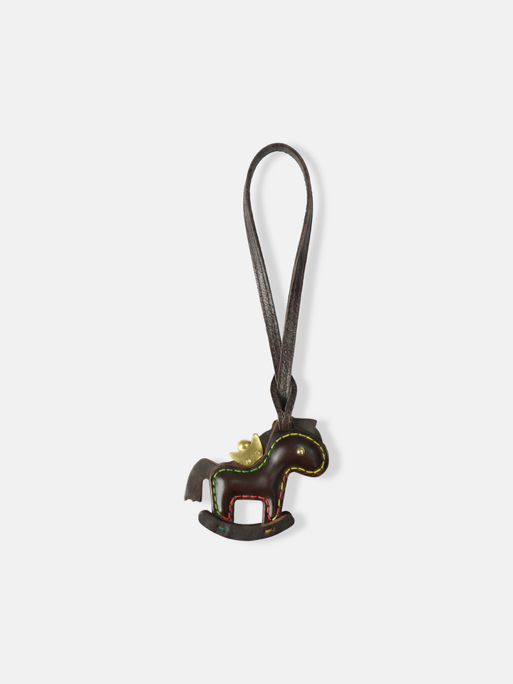 Deep green leather rocking horse bag charm with a gold-tone crown, compact and graphic, attached to a bag.