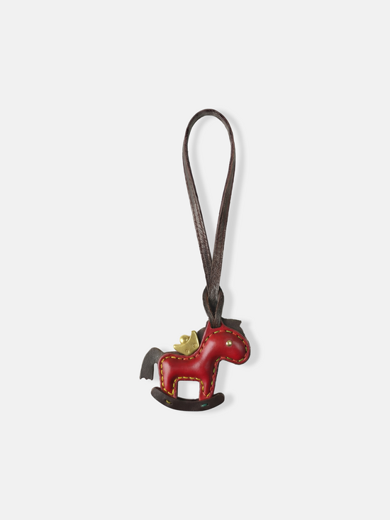 Deep green leather rocking horse bag charm with a gold-tone crown, compact and graphic, attached to a bag.
