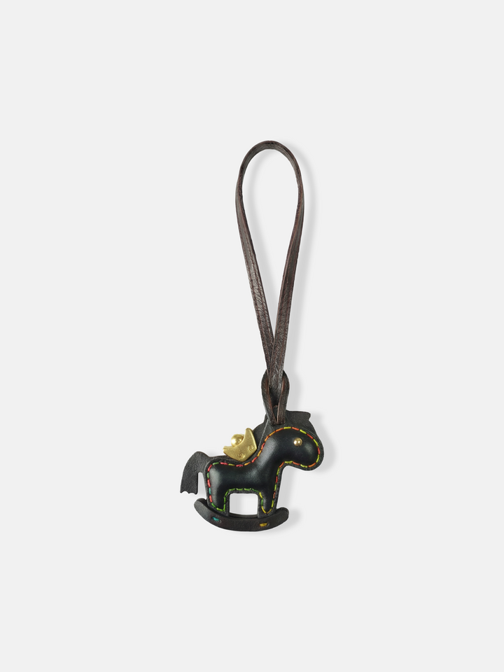 Deep green leather rocking horse bag charm with a gold-tone crown, compact and graphic, attached to a bag.