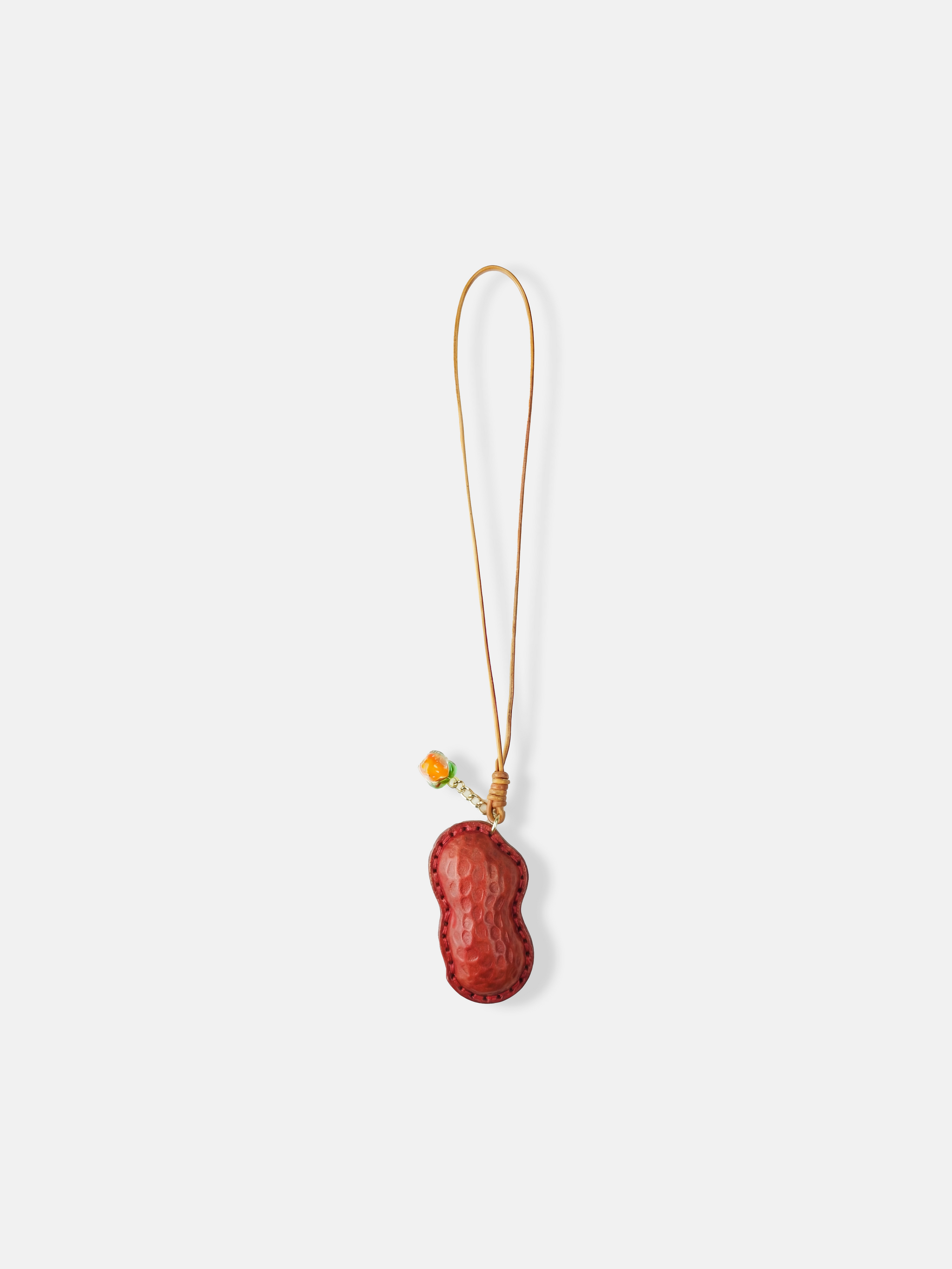 Selvane Peanut Pod Bag Charm, a sculpted leather peanut silhouette with contrast stitching, attached to a slim strap.