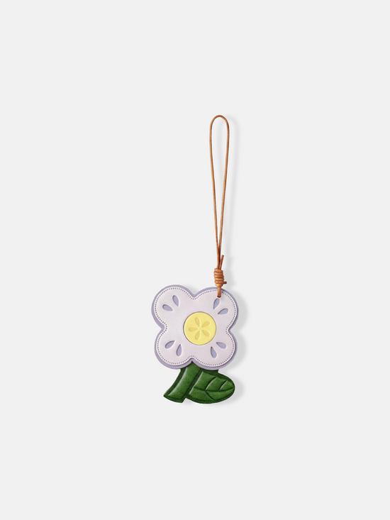 Selvane Flower Bag Charm, a graphic leather bloom with rounded petals and a cutout motif, suspended by a slender lanyard.