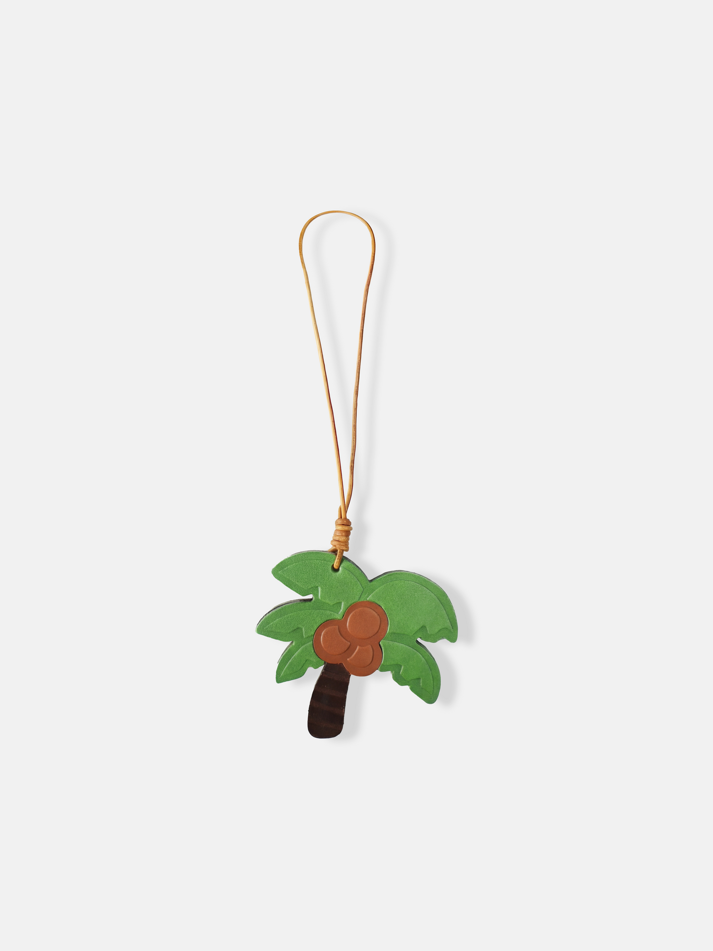 Selvane Coconut Palm Bag Charm, featuring a crisp, graphic palm silhouette with layered fronds and a rounded coconut cluster, attached to a bag.