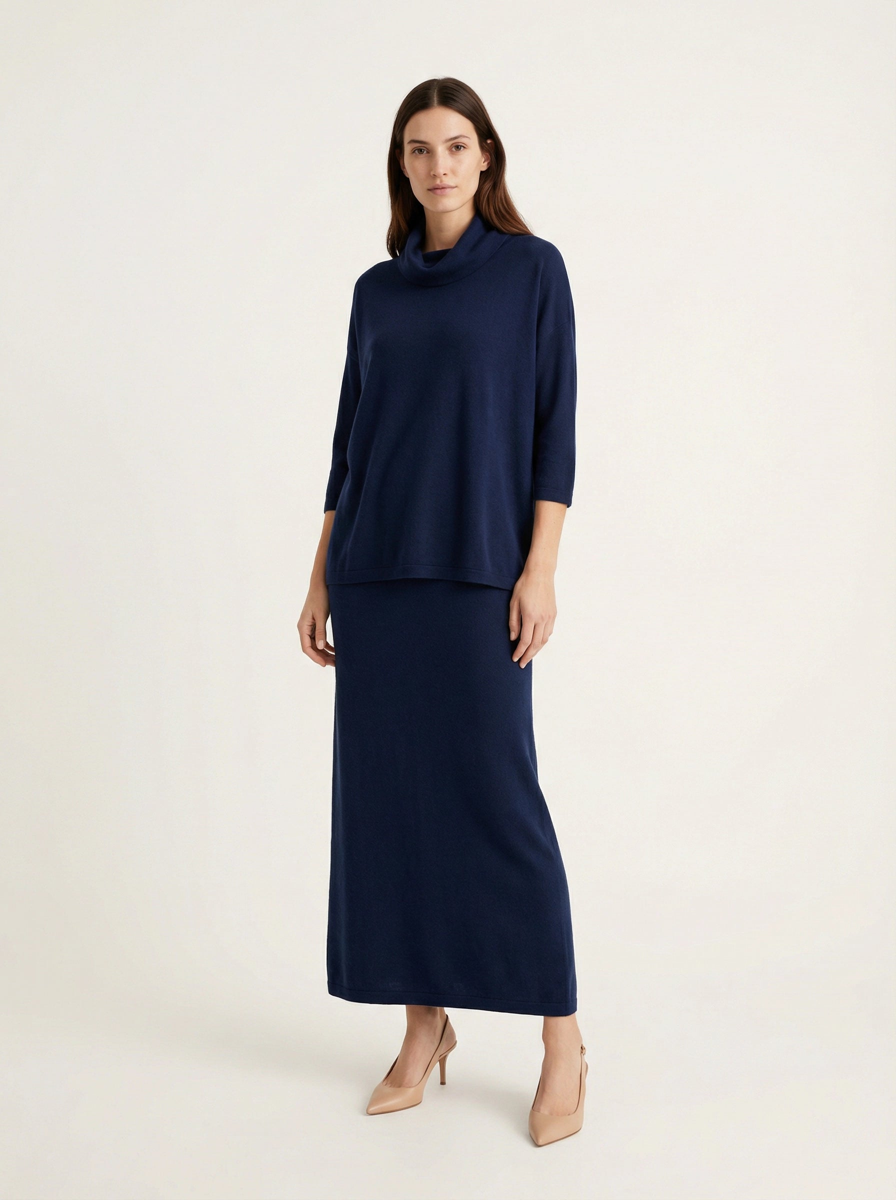 Model wearing a deep navy Tencel-blend cowl-neck top and matching midi pencil skirt set, styled elegantly.