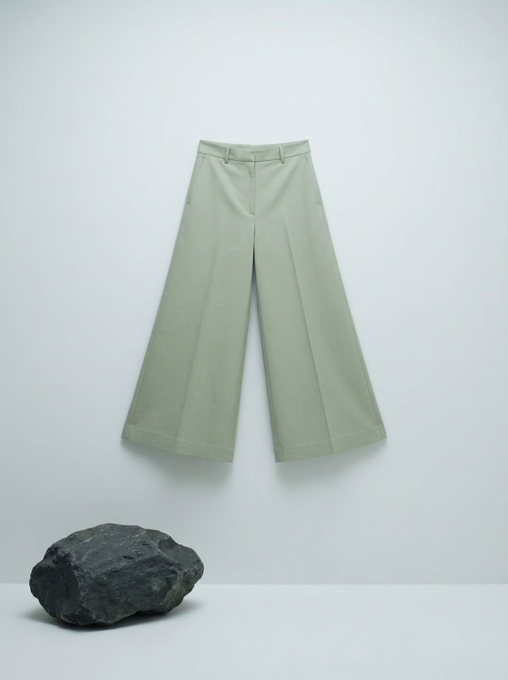 Model wearing SELVANE sage green ribbed knit tank and high-waisted wide-leg trousers set, standing elegantly.