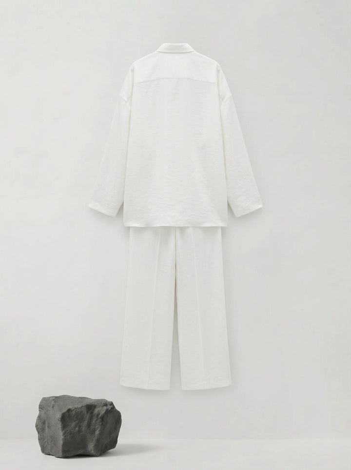 SELVANE pure white bow-tie blouse and wide-leg trousers set in luminous, crinkled acetate fabric, styled elegantly.