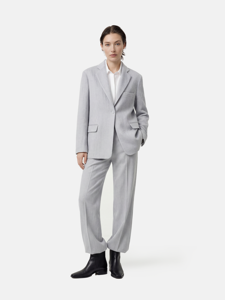 Structured worsted wool jacket with mulberry silk lining, tailored fit, shown on a model in a thoughtful pose.