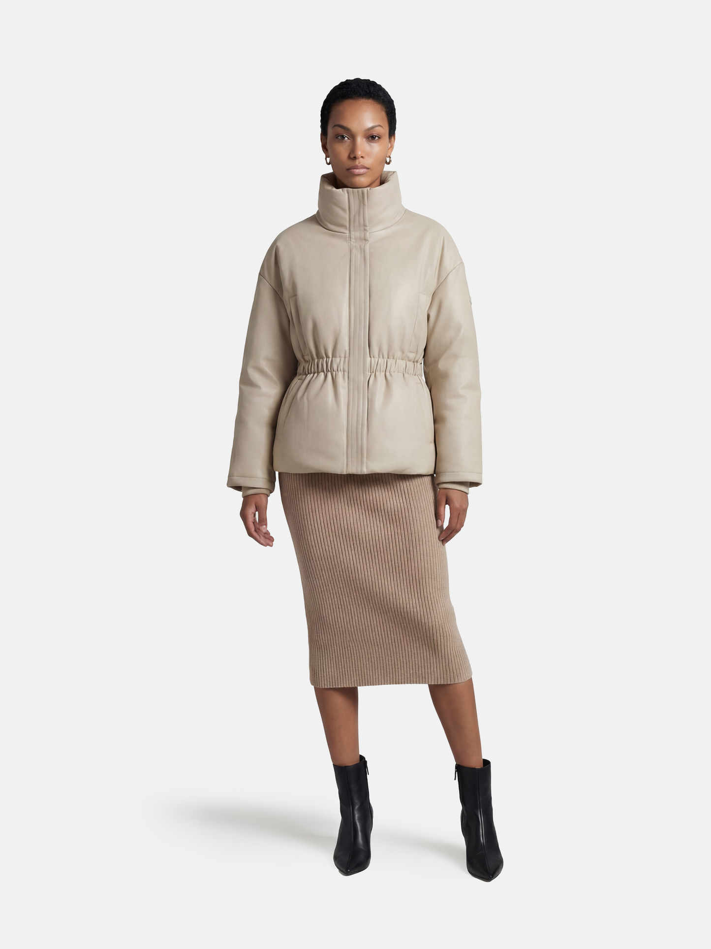 Apricot high-collar structured puffer down jacket by SELVANE, featuring a concealed placket and cinched waist, presented architecturally.