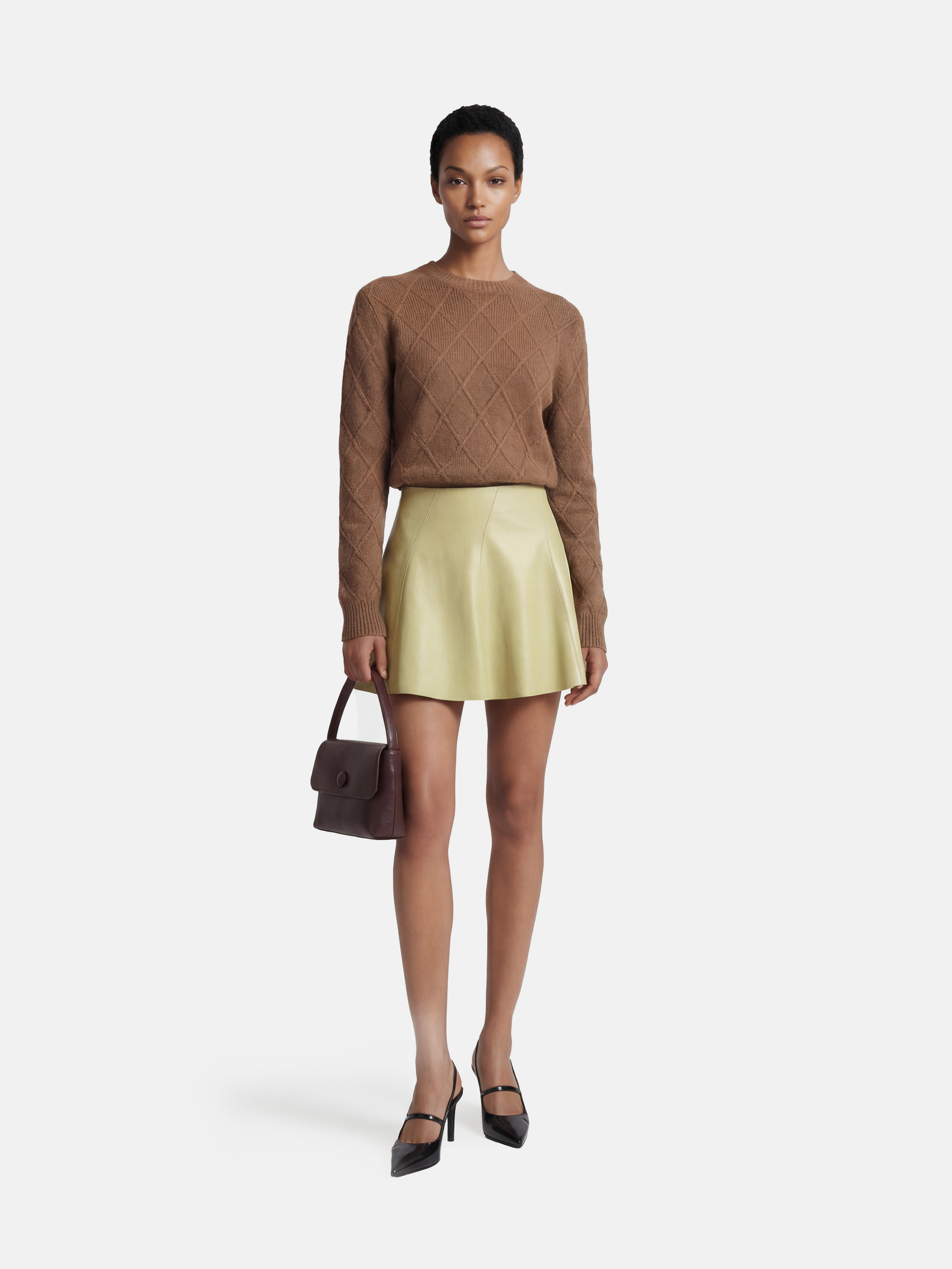 Soft yellow high-waist lambskin miniskirt with a gentle A-line silhouette, showcasing its supple texture and precise cut.