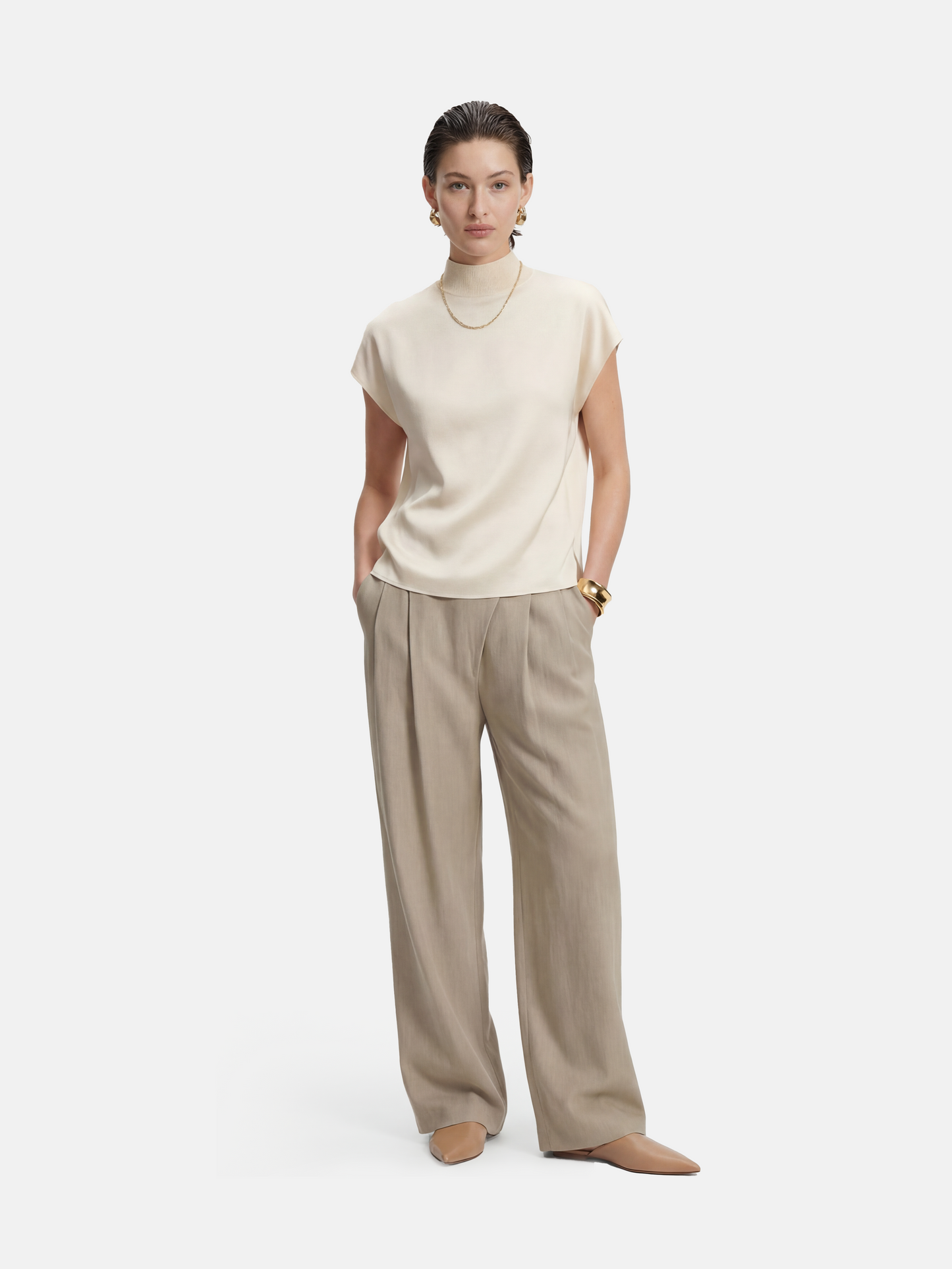 Cropped wide-leg trousers in quiet khaki, featuring deep pleats and an asymmetric front, embodying architectural form and fluid motion.