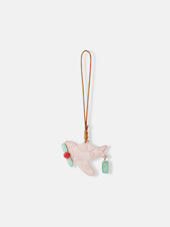 Polished metal Selvane Dream Plane Bag Charm, featuring a sleek aircraft silhouette and 'That's my dream' tag, symbolizing personal journeys.