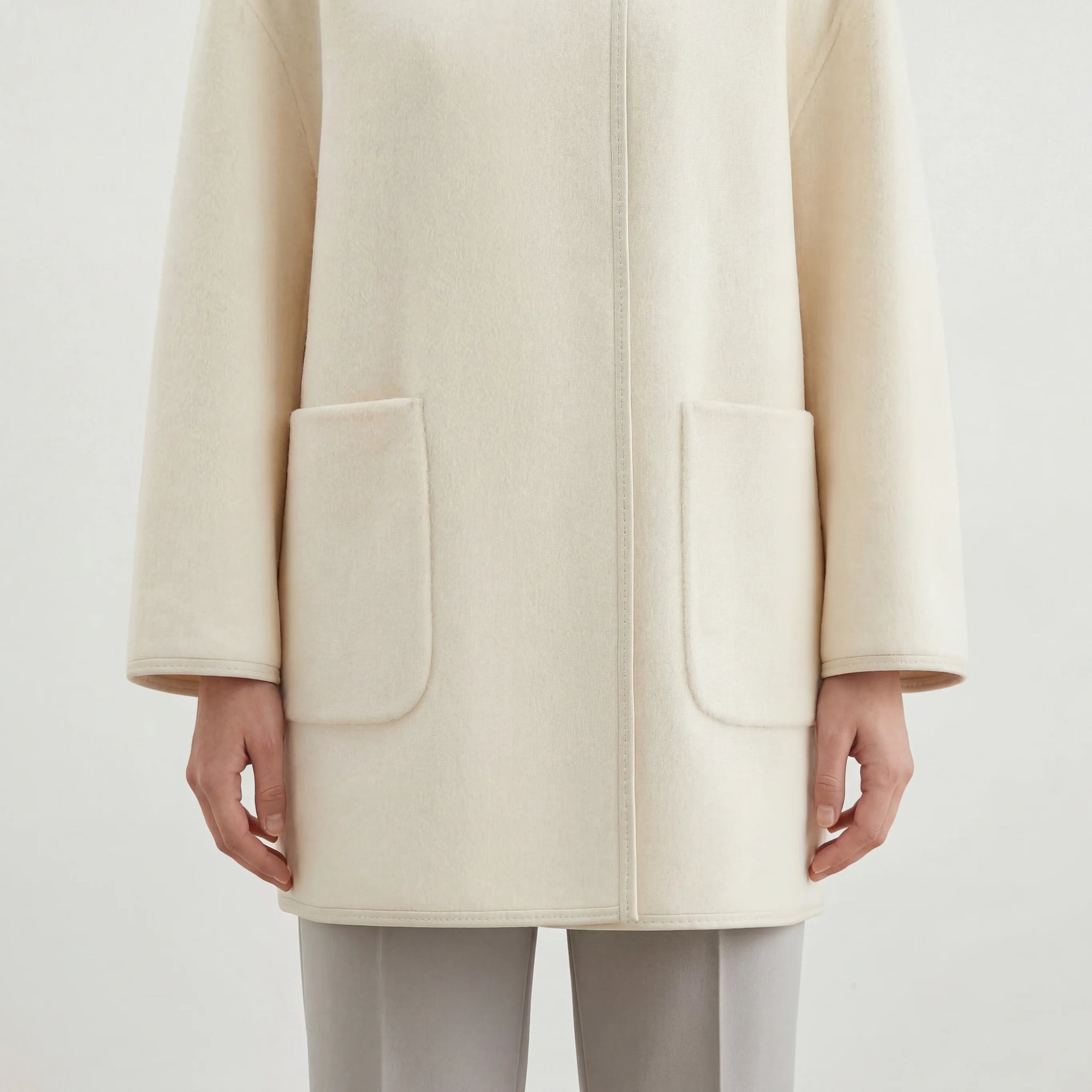 SELVANE asymmetric single-button wool coat in calm ivory, featuring a clear line and composed silhouette.