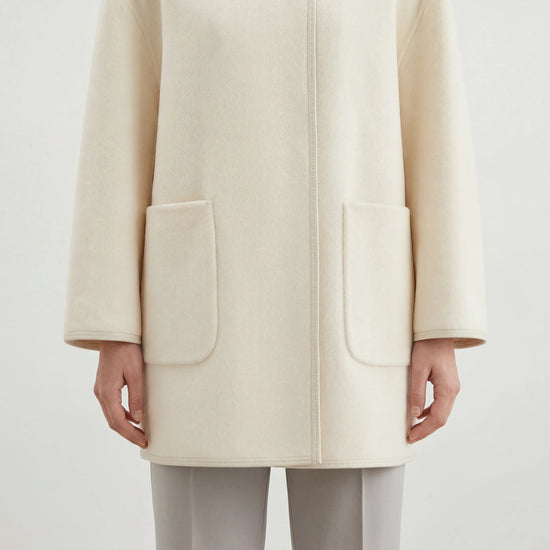 SELVANE asymmetric single-button wool coat in calm ivory, featuring a clear line and composed silhouette.