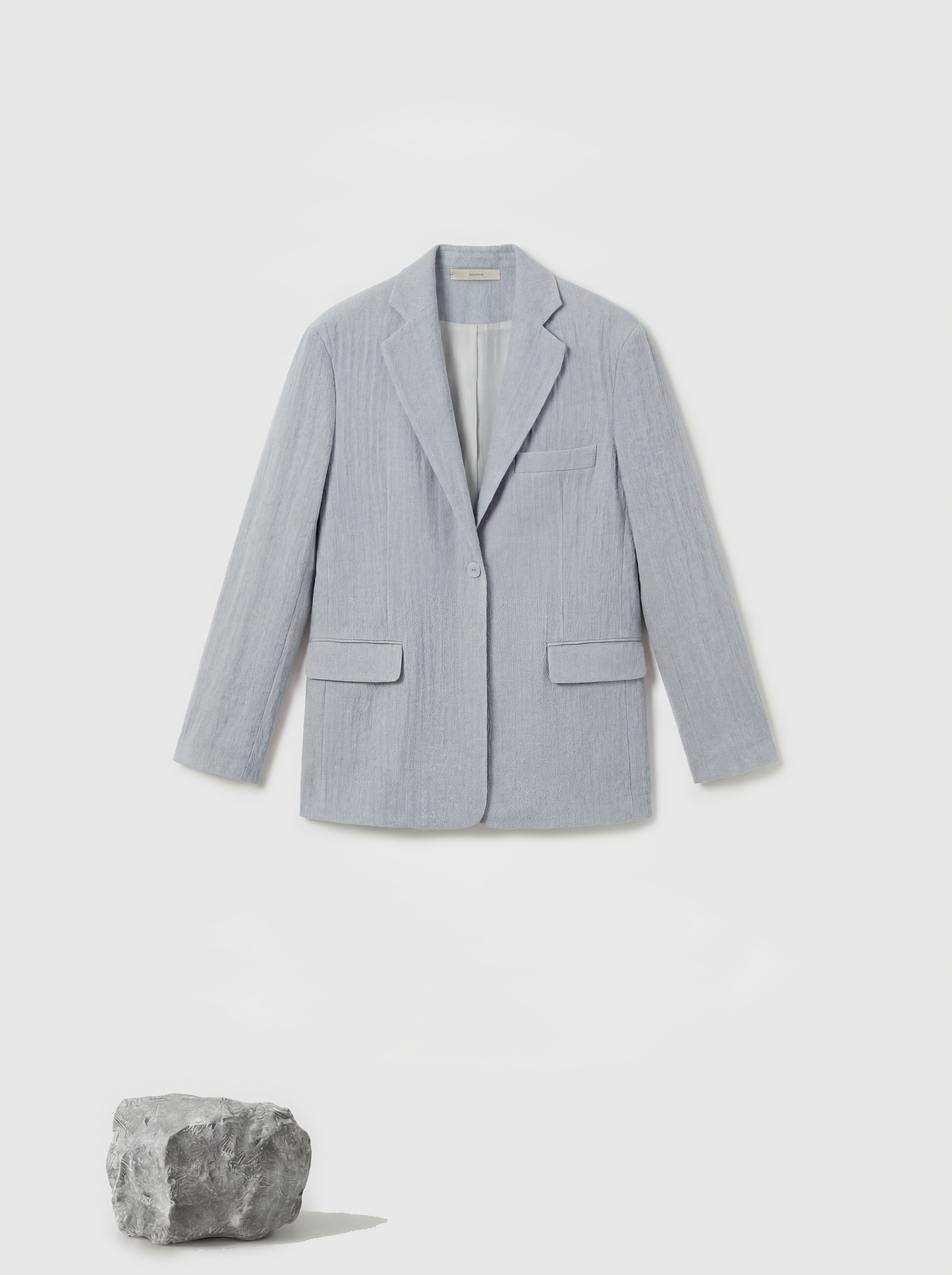 Structured worsted wool jacket with mulberry silk lining, tailored fit, shown on a model in a thoughtful pose.